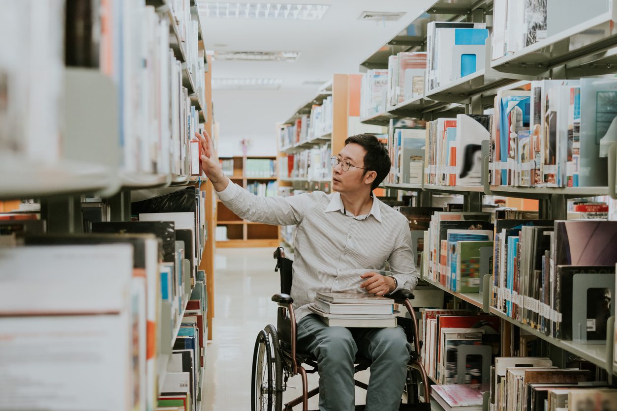 Man in wheelchair browsing library books