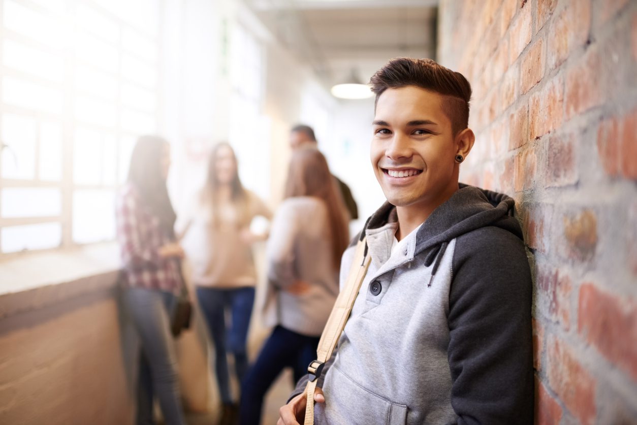 Student in hallway leaning against brick wall