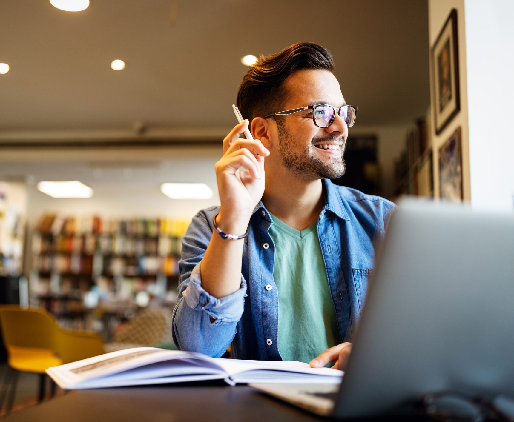 Student looking out window with laptop in library